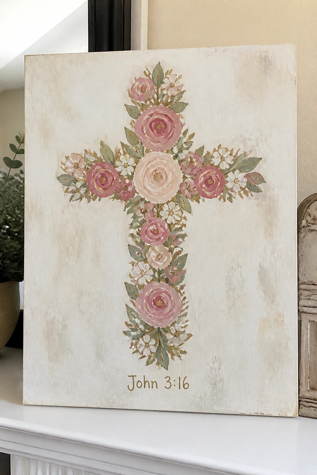 Floral cross of pink roses and white flowers on off-white canvas with John 3:16 below