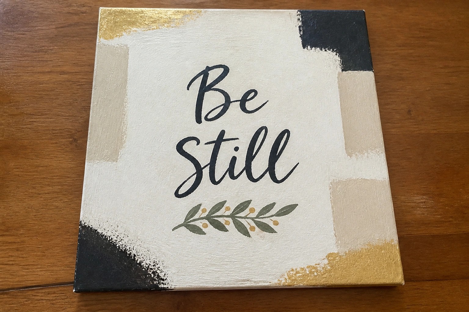 Abstract canvas with black and gold brushstrokes, "Be still" text, and gold leaves.