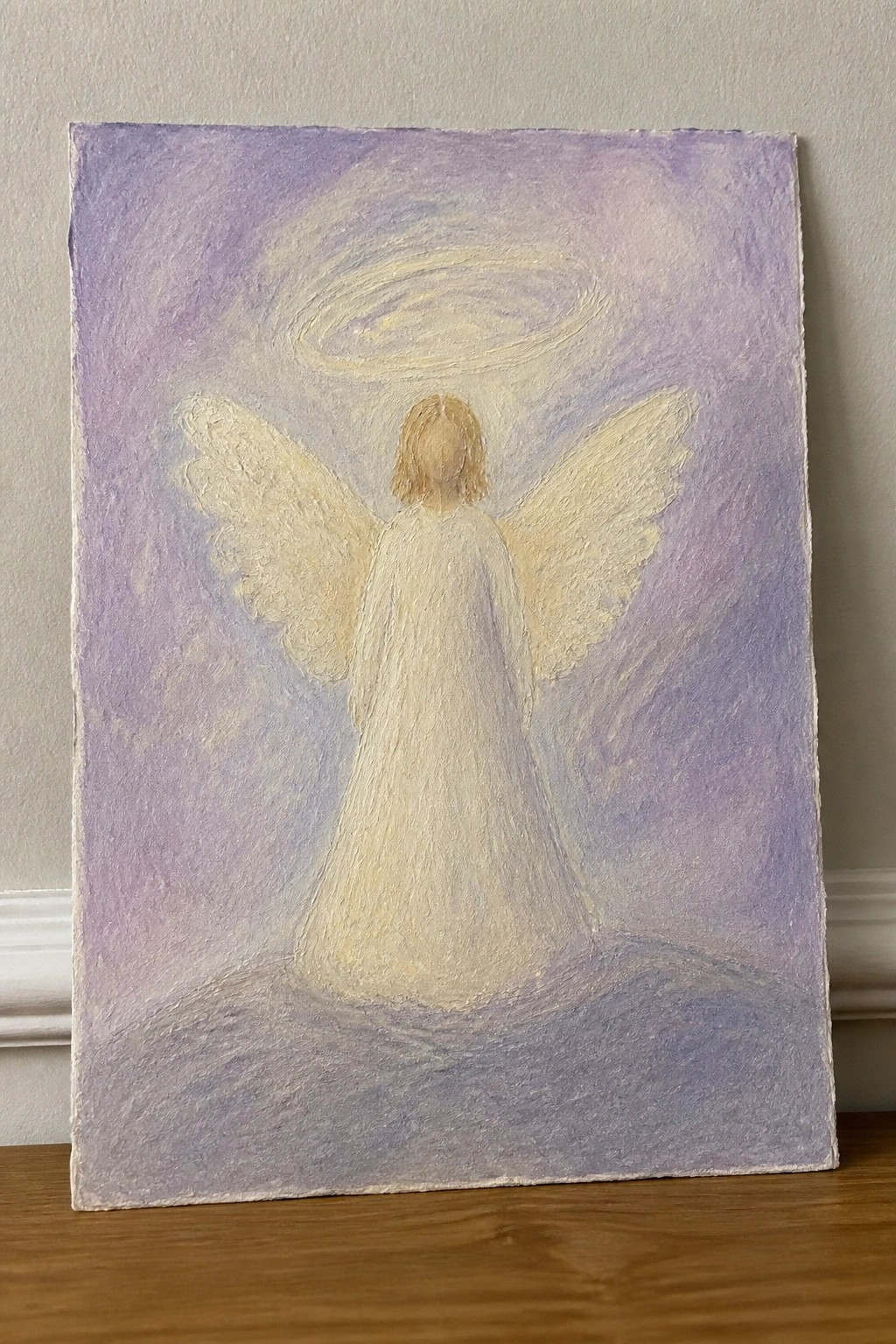 Angel in flowing white robe with large wings and golden halo against purple background