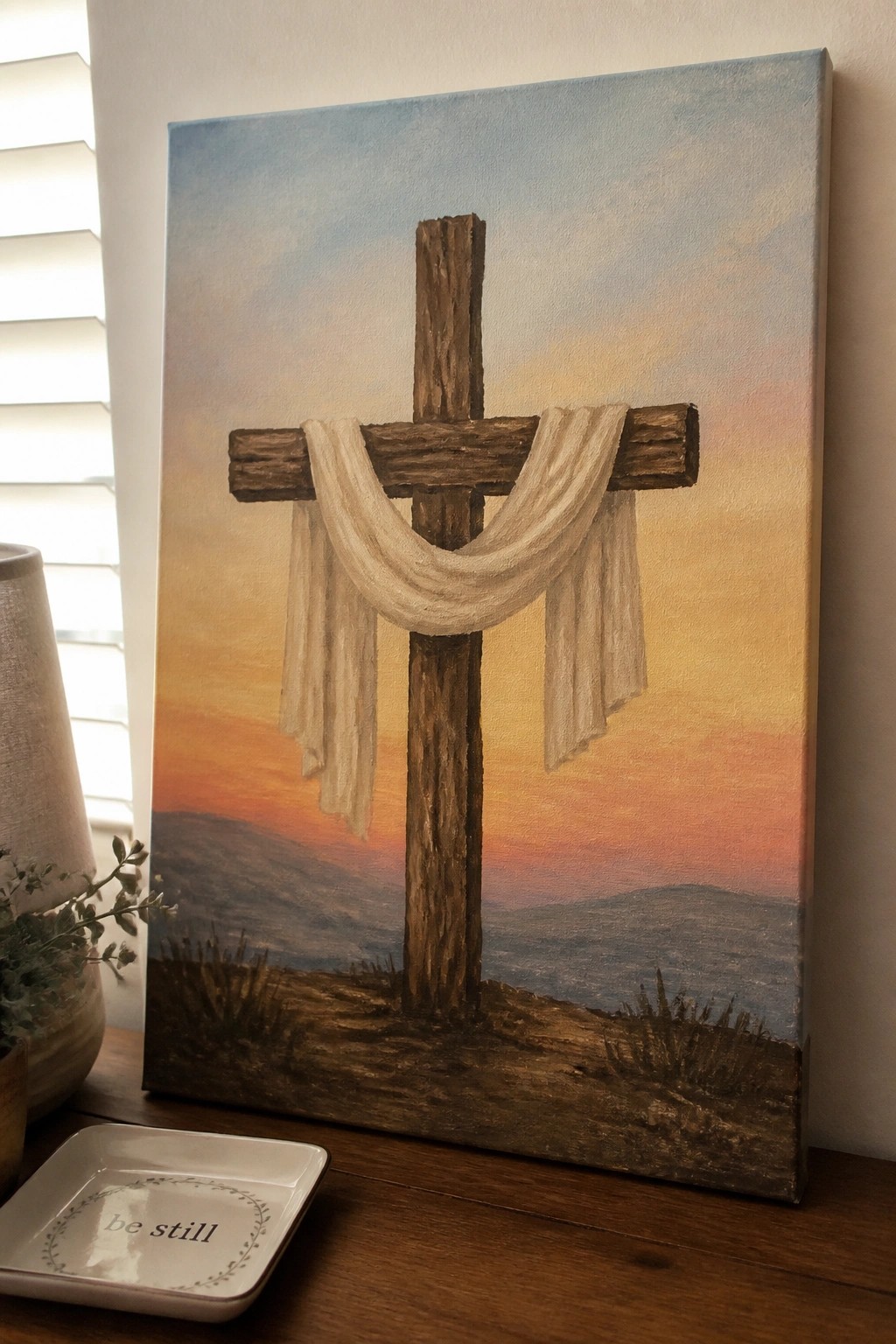 Canvas painting of wooden cross with white cloth against vibrant sunset sky