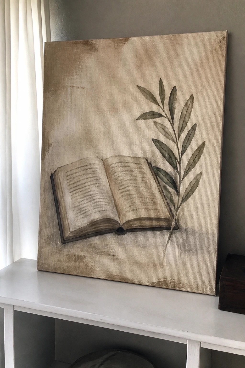 Textured beige canvas painting of an open book beside a leafy green branch