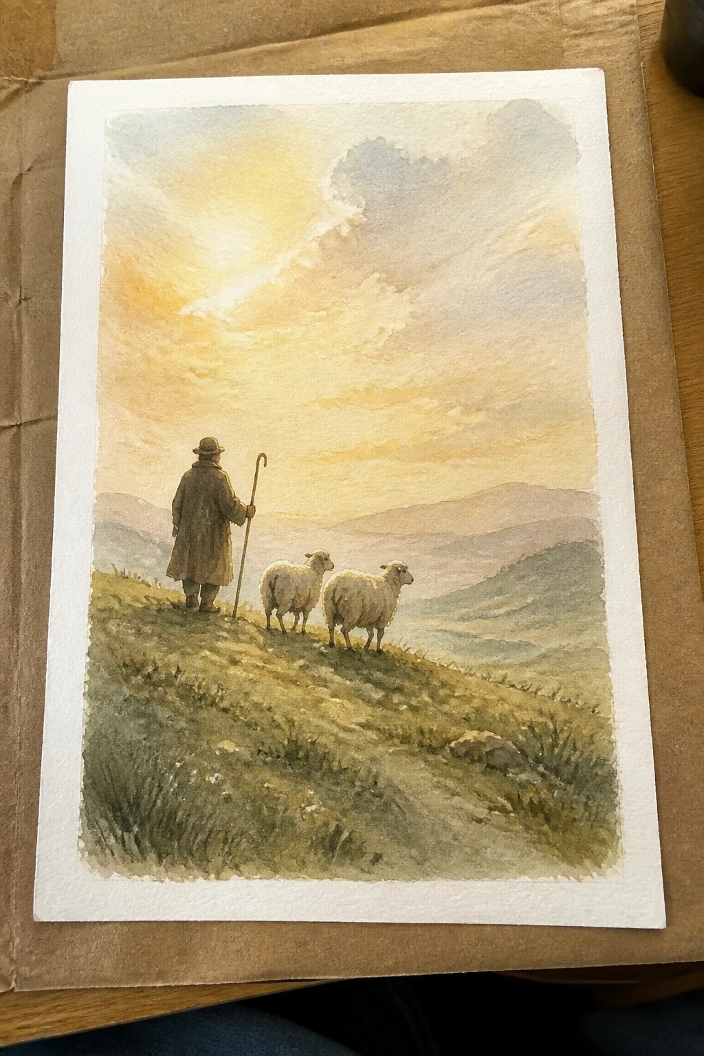 Watercolor of shepherd in brown coat and hat with staff beside two sheep on hillside at sunset
