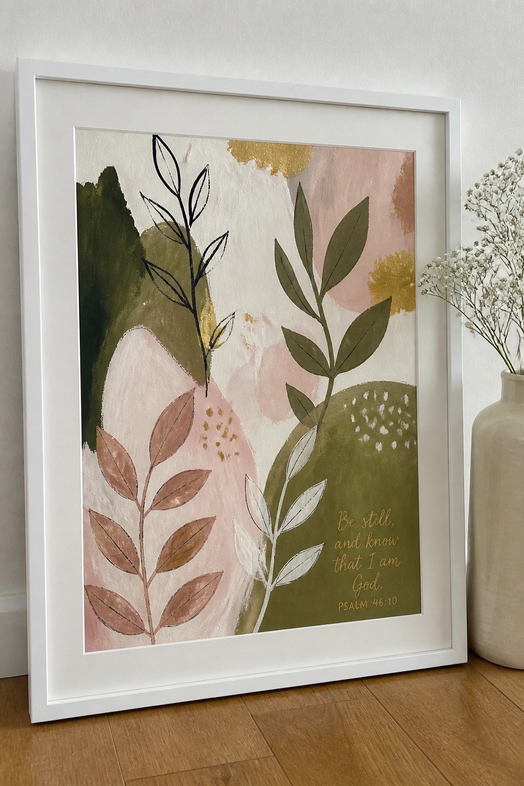 White-framed abstract leaf art with gold Psalm verse beside white floral vase