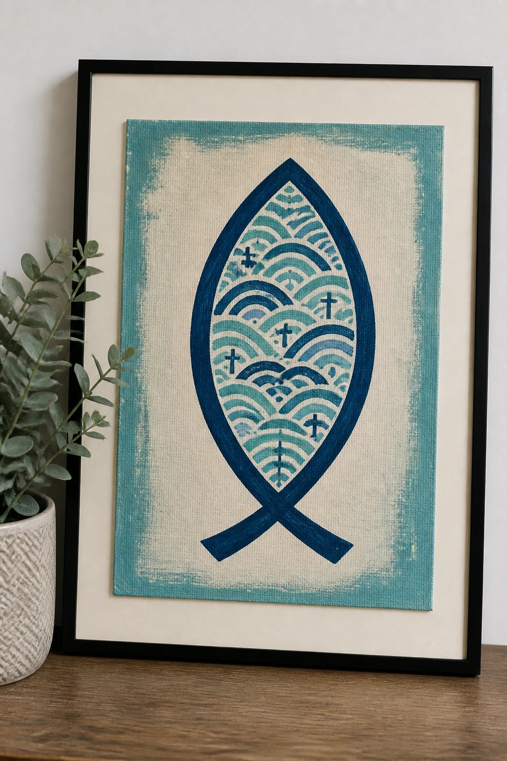 A framed canvas shows a blue ichthys fish outline filled with layered wave patterns and small crosses on a textured background.