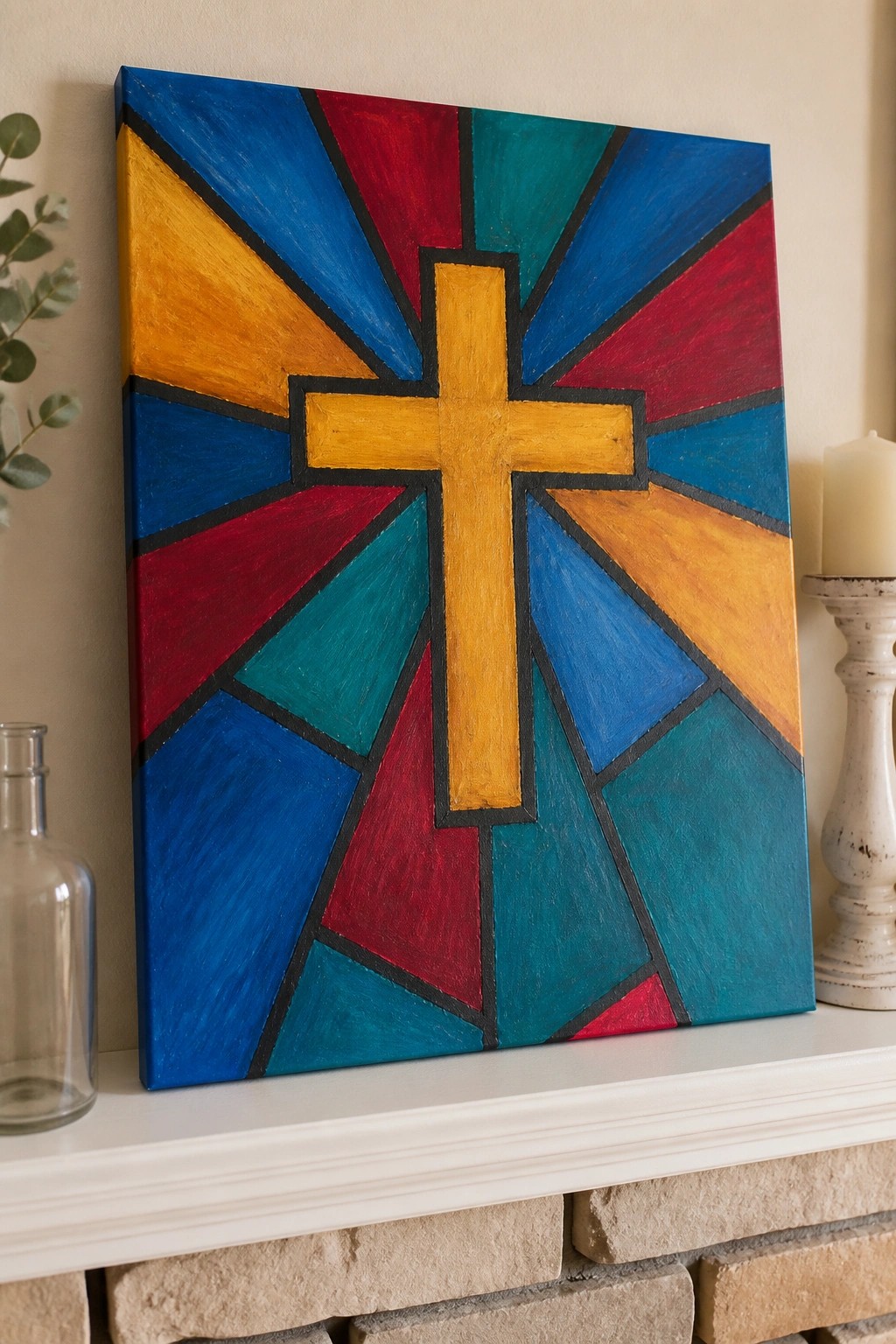 Colorful stained-glass style cross painting on white mantel with candle and bottle