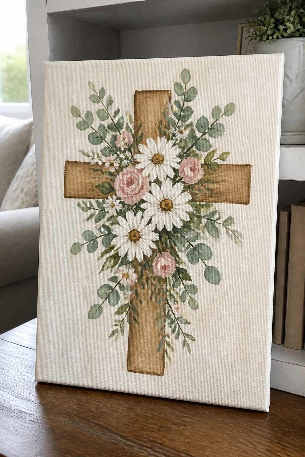Watercolor canvas painting of brown cross with white daisies, pink roses, and eucalyptus.