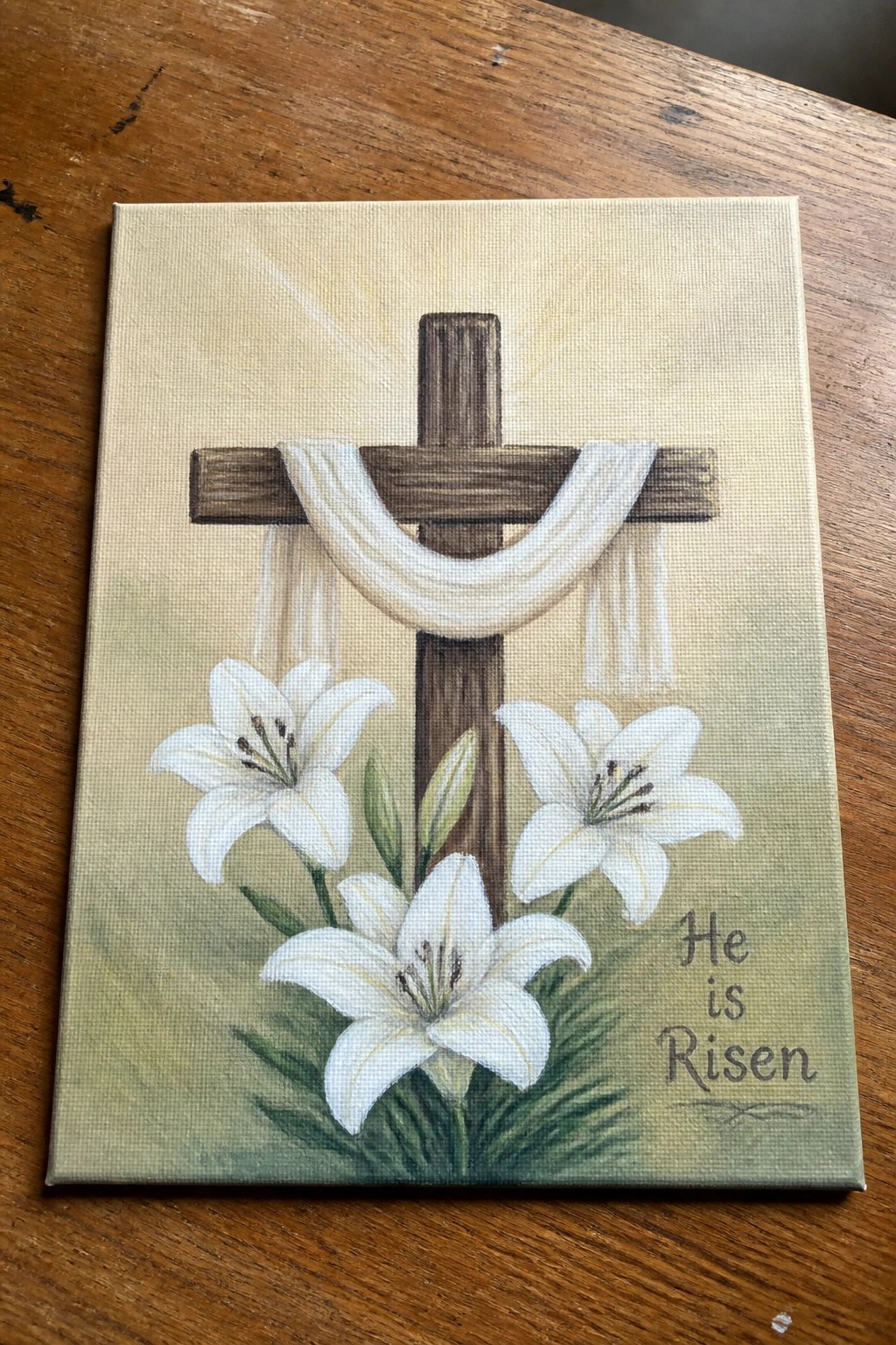 Canvas painting of wooden cross with white cloth, lilies, and 