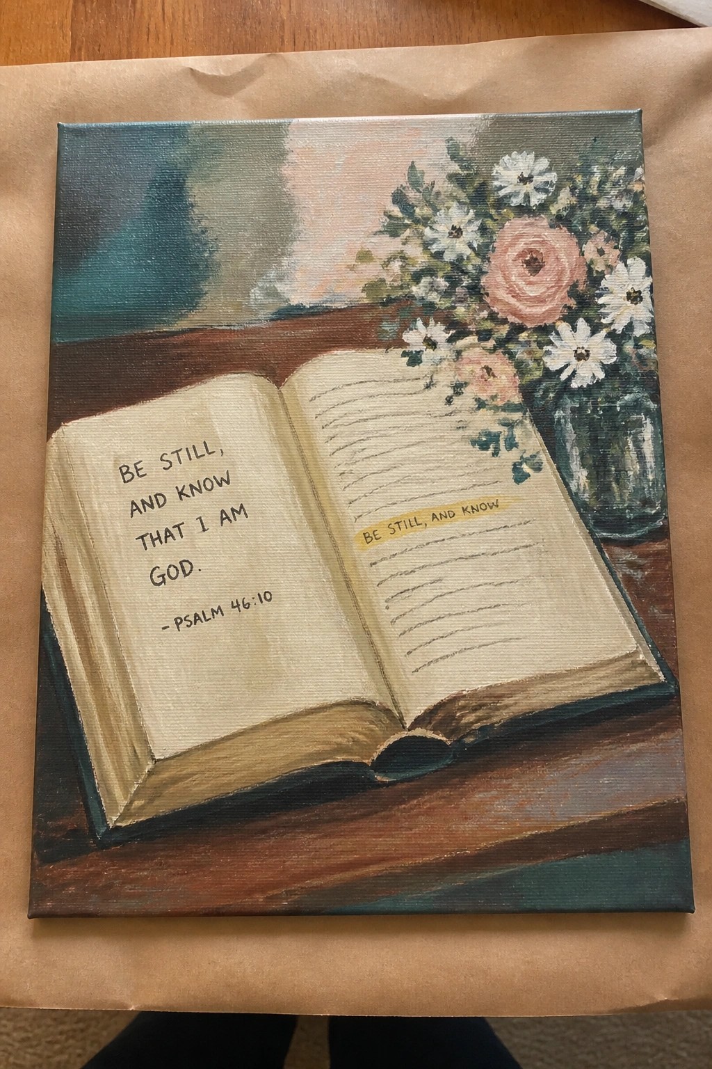 Open Bible with Psalm 46:10 beside pink roses and white daisies in glass vase on table