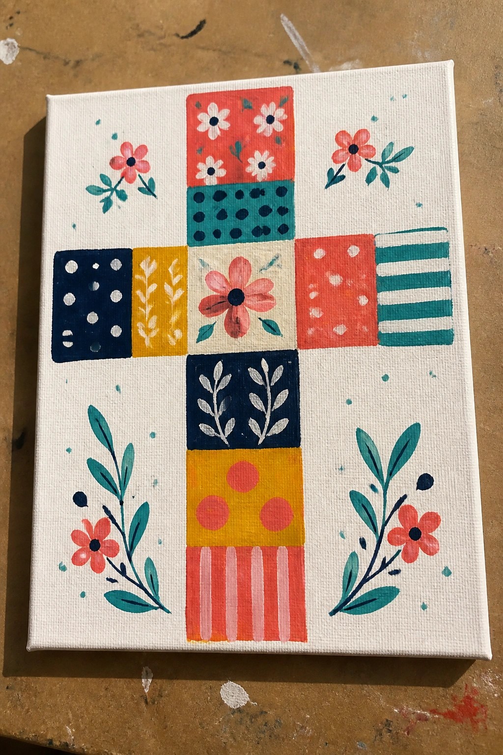 Colorful patchwork cross of patterned squares with pink flowers on white canvas