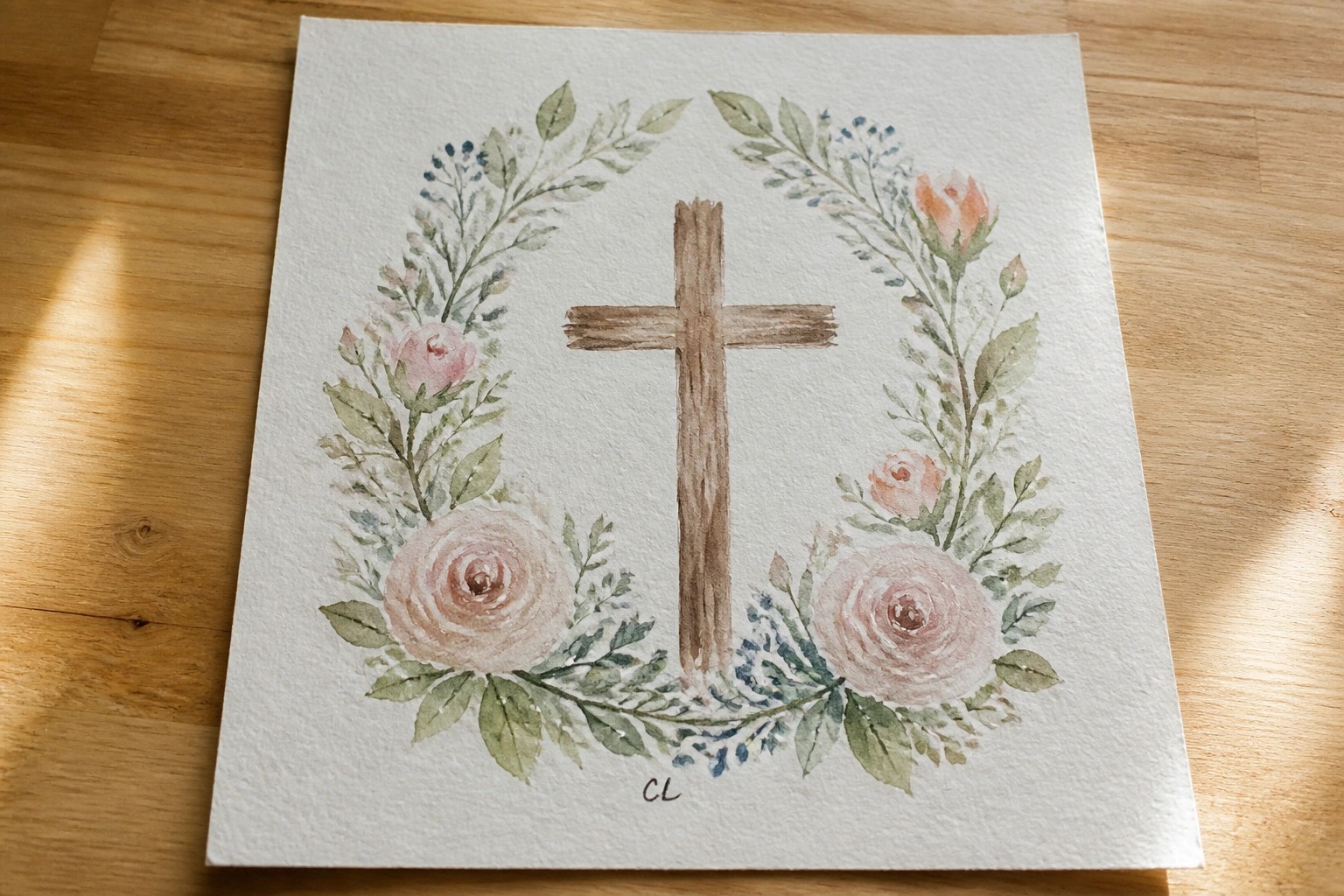 Watercolor cross centered in wreath of pink roses and green leaves on paper