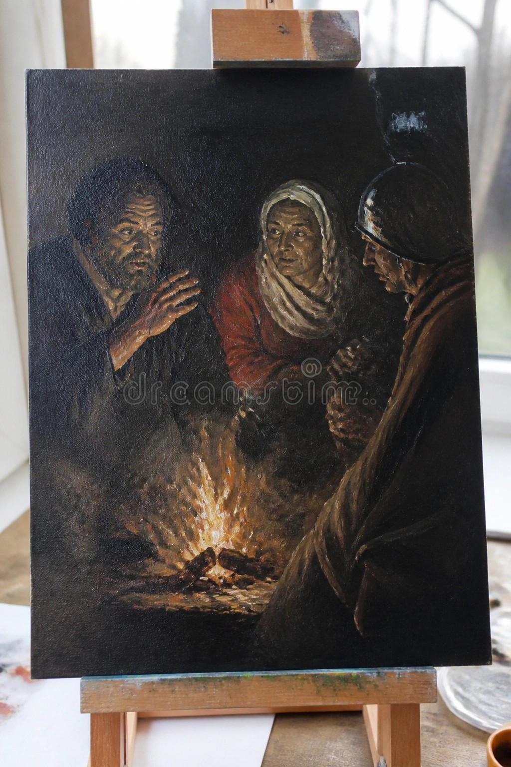 A painting on an easel depicts three people gathered around a small fire in a dark setting.