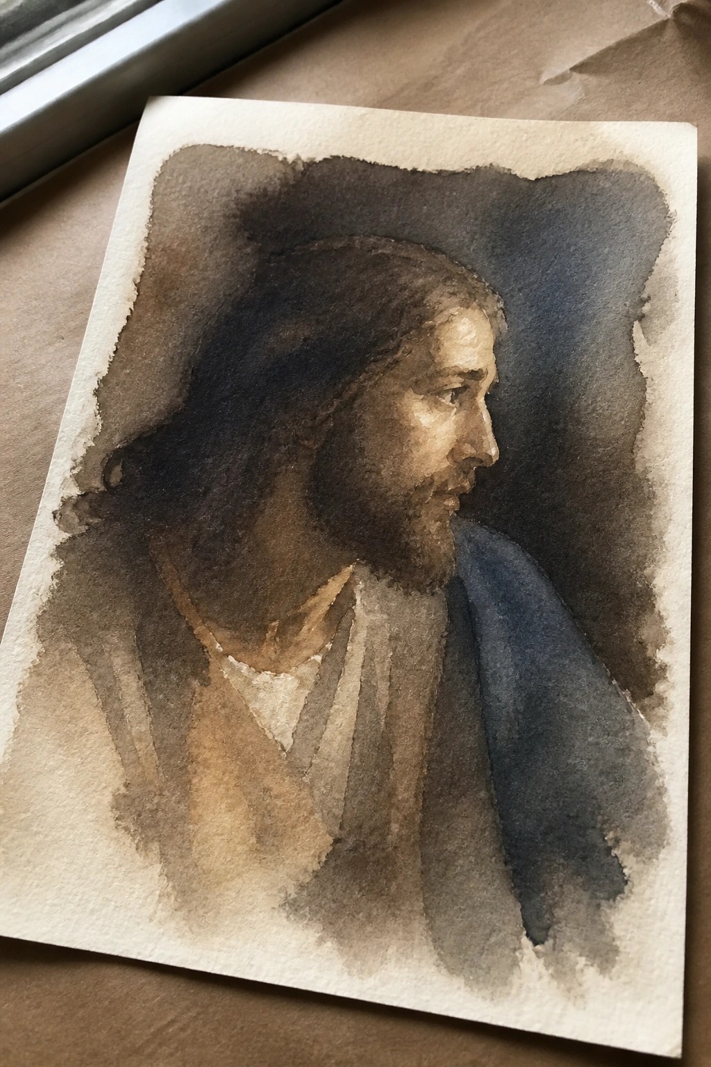 Watercolor portrait of long-haired bearded man in profile wearing brown robes with blue drape.