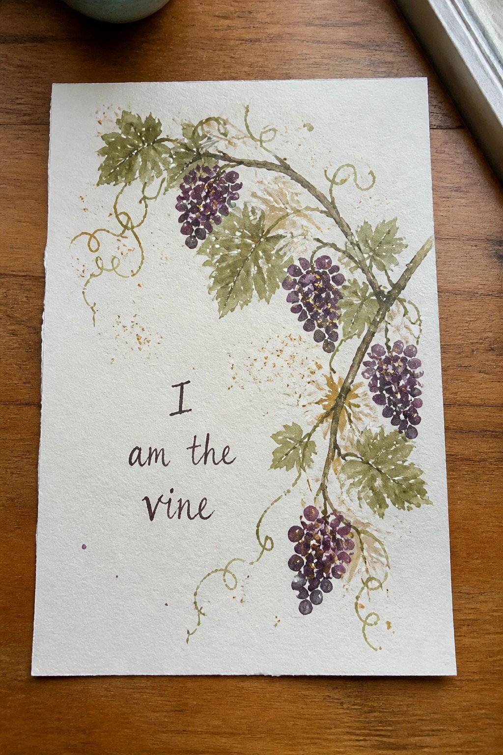Watercolor painting of purple grapes on vines with green leaves and text 