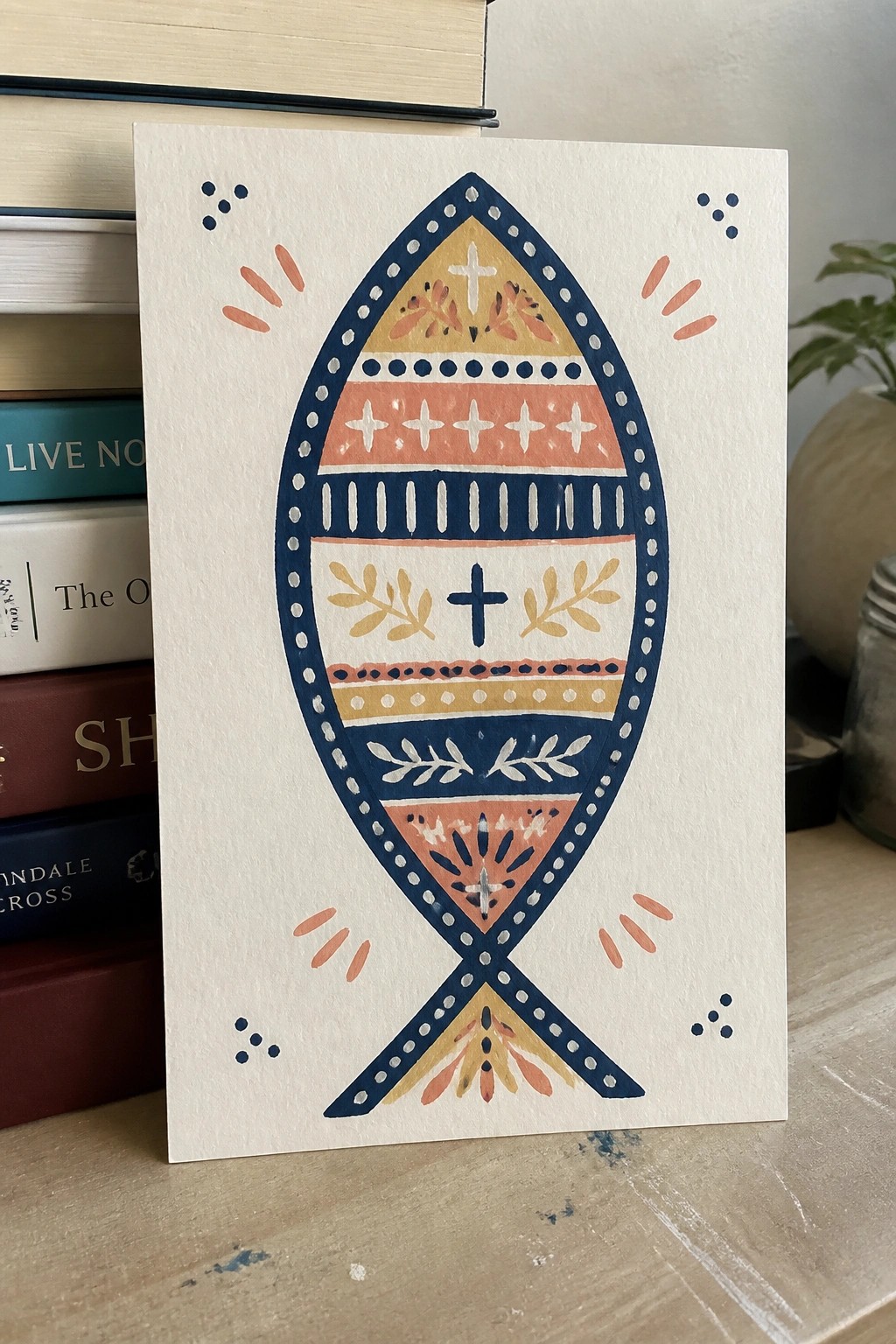 Colorful patterned fish symbol with crosses on white card against books.