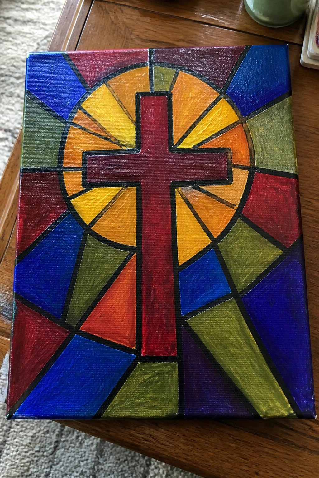 Stained-glass style painting with red cross and rainbow geometric sections on canvas