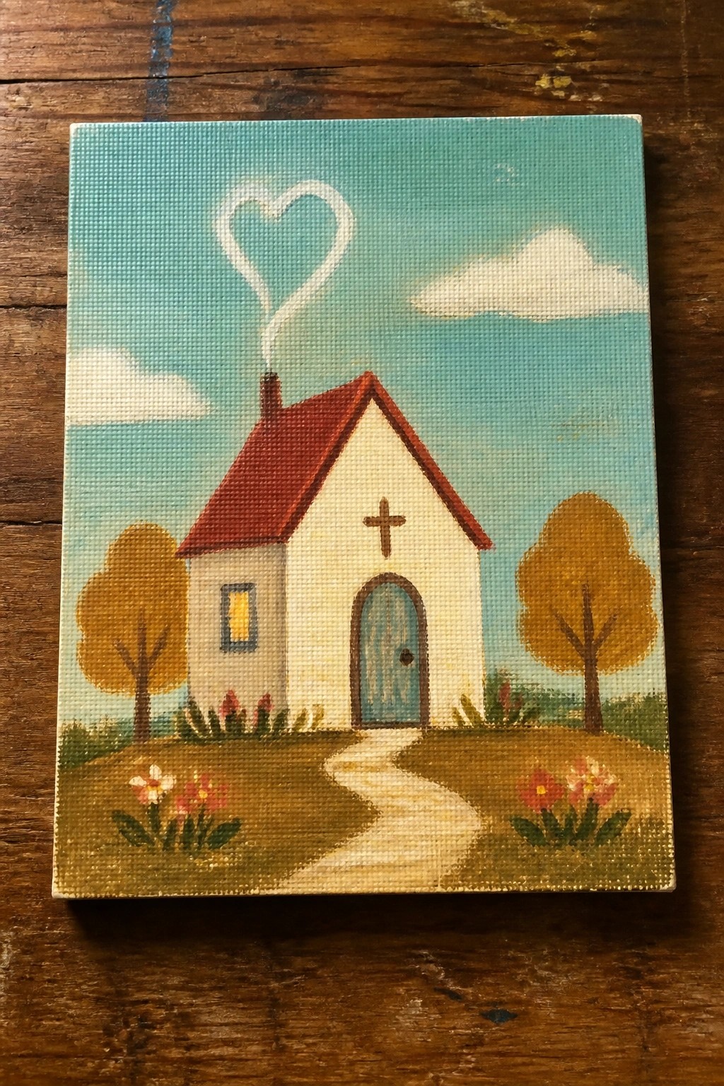 Folk art painting of white church with red roof, blue door, and heart-shaped chimney smoke.