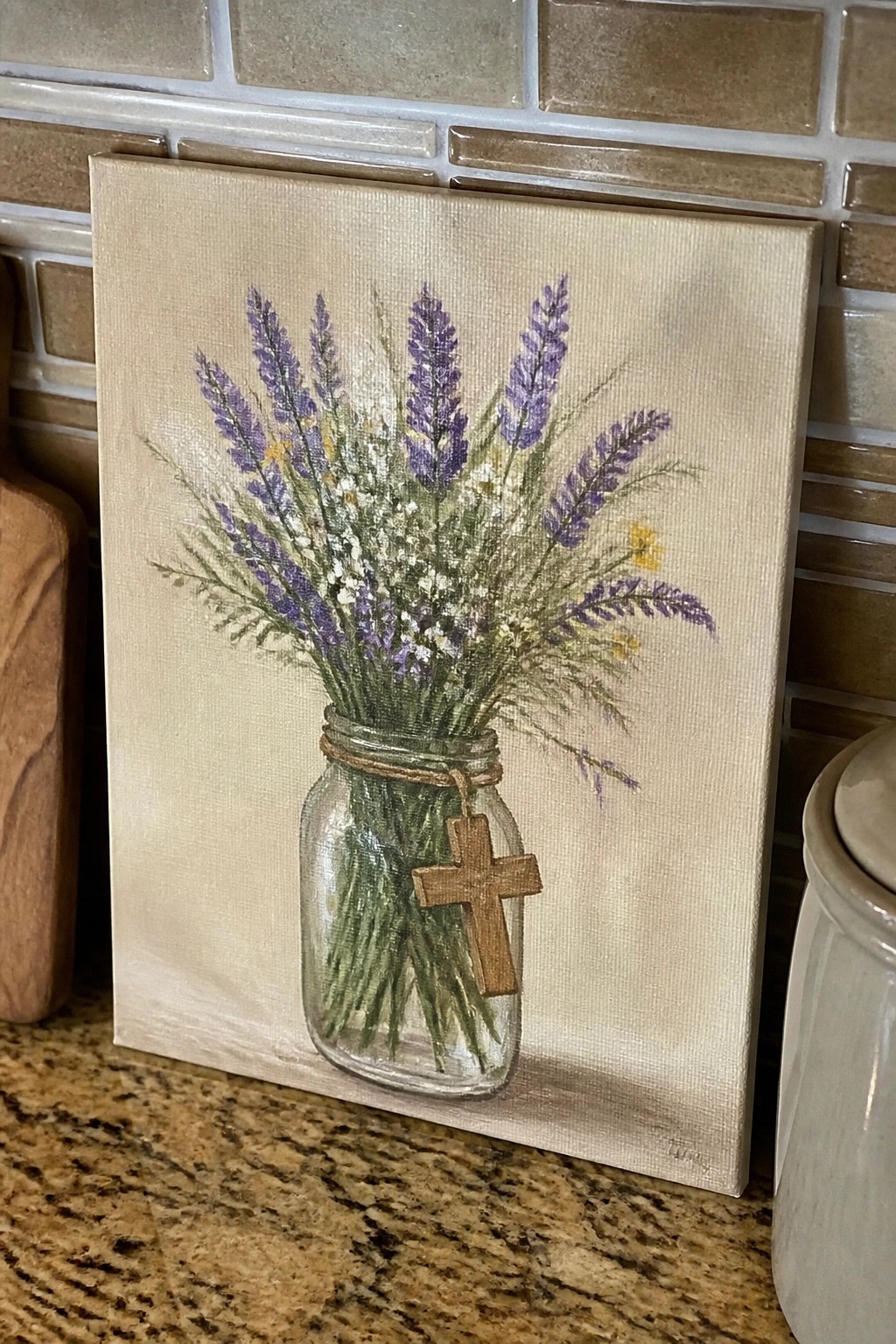 Painting of lavender bouquet in glass mason jar with wooden cross on counter
