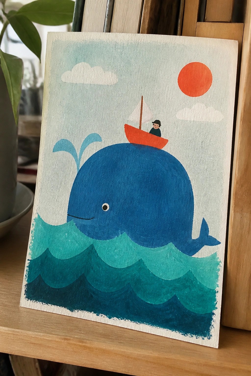 Watercolor painting of blue whale with red boat and sailor atop wavy ocean under red sun