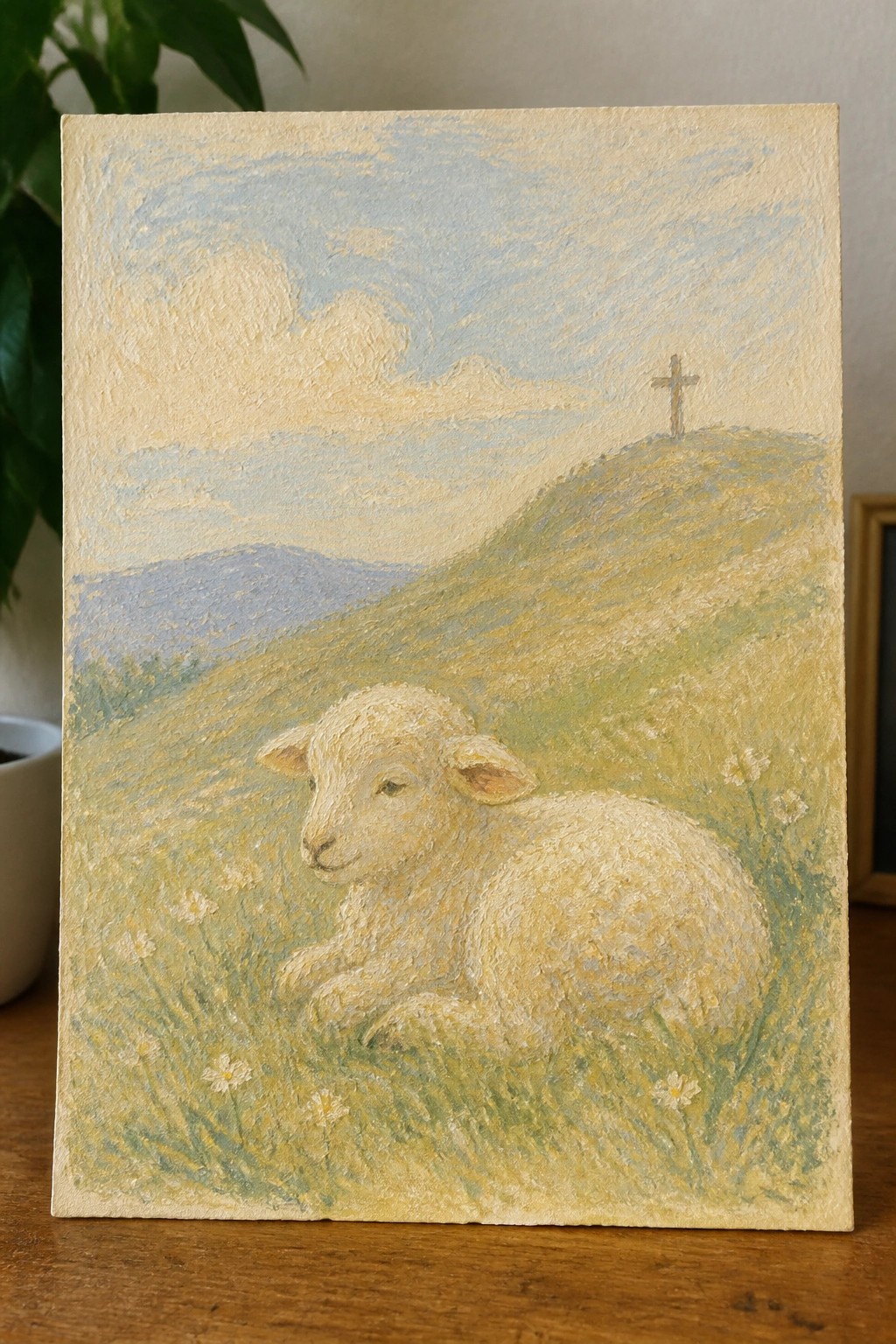 A lamb rests in a flower-dotted meadow beneath a hilltop cross.