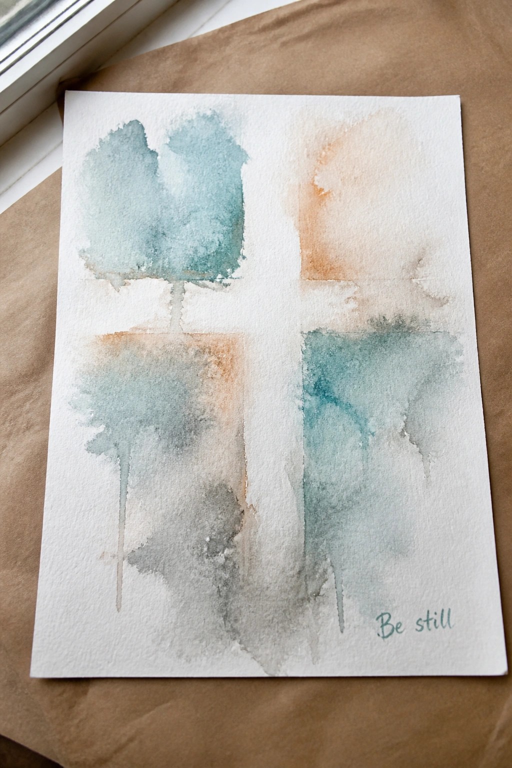 Abstract watercolor in teal, orange, and gray washes on white paper with
