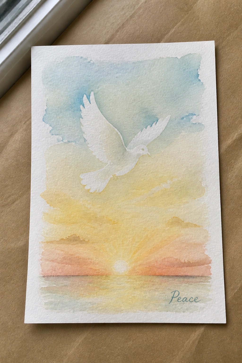 Watercolor of white dove flying over sunset reflecting on water, with