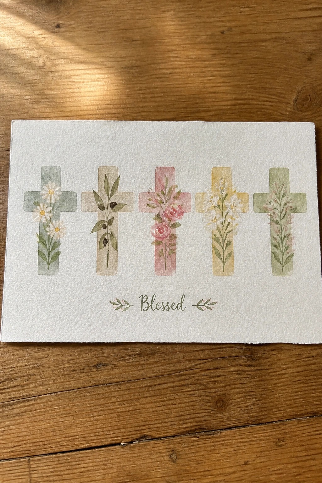 Five floral watercolor crosses in soft pastels above the word Blessed on paper