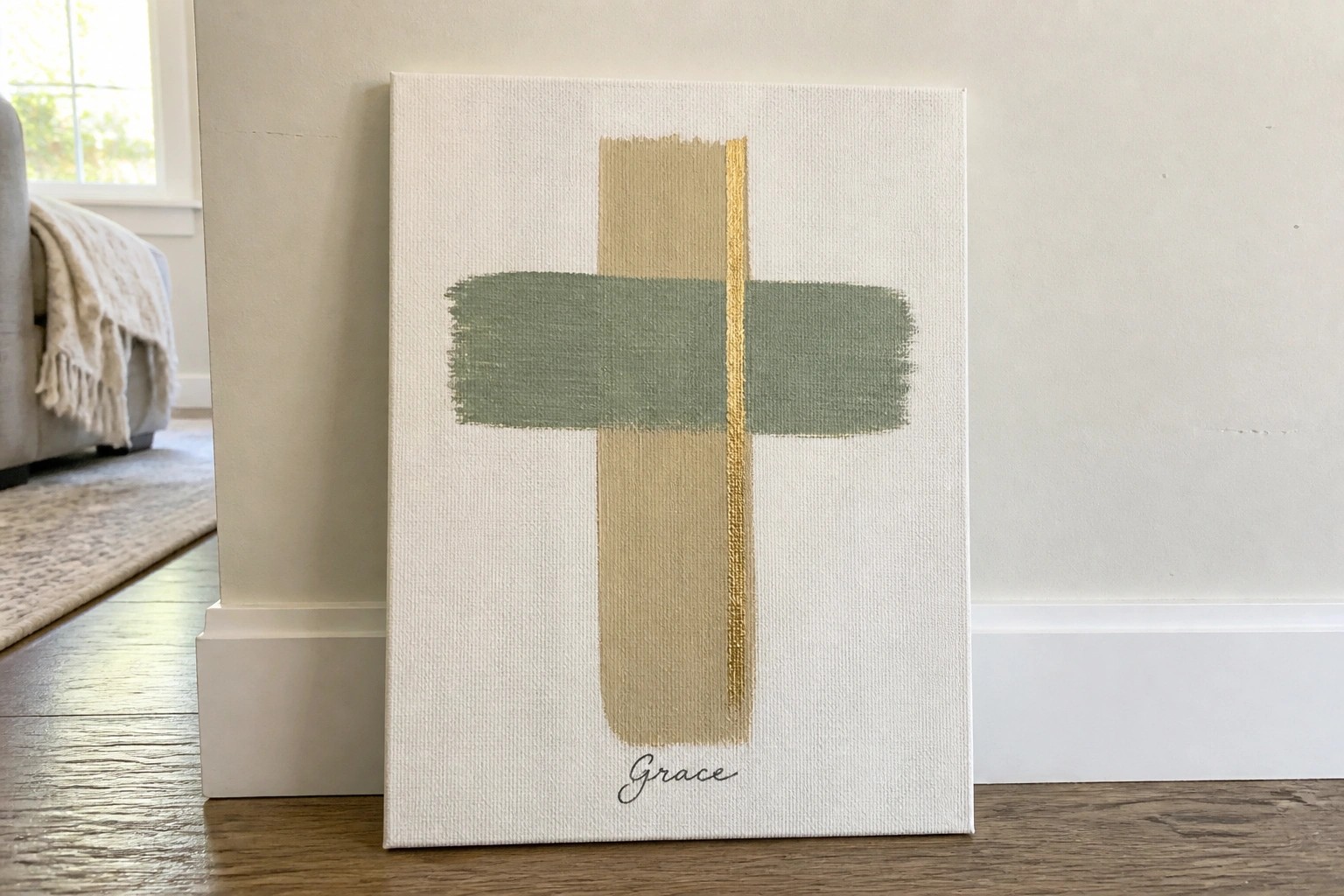 Abstract cross in beige, sage green, and gold on cream canvas with "grace" below