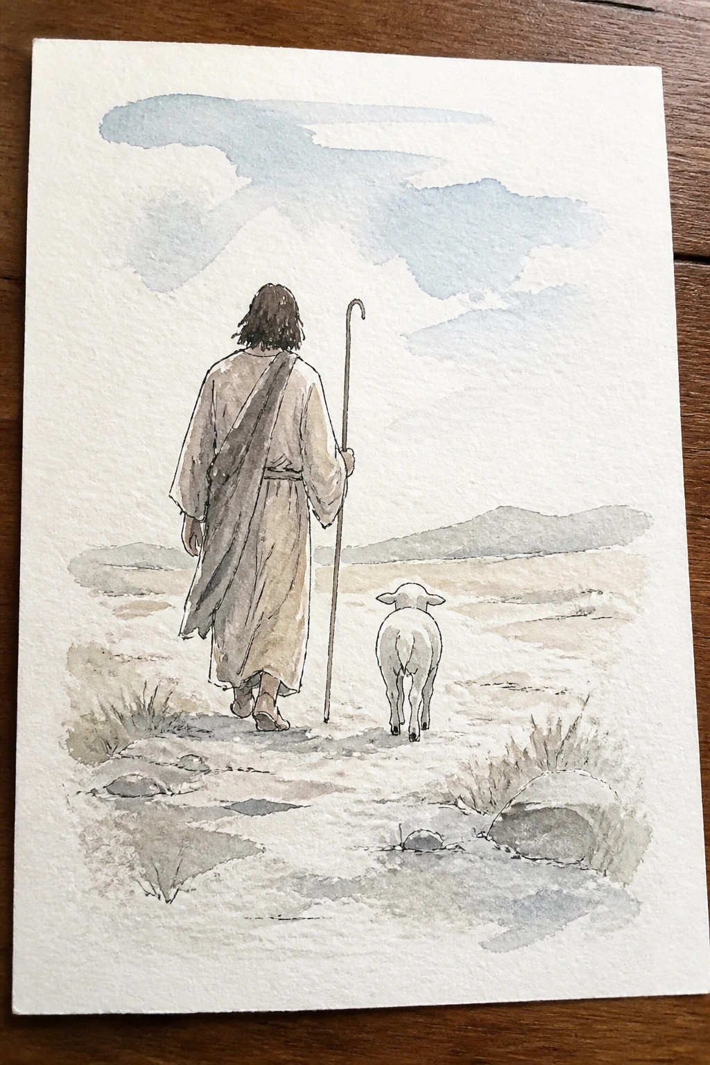 Watercolor of robed shepherd with staff walking behind a lamb on a desert path.