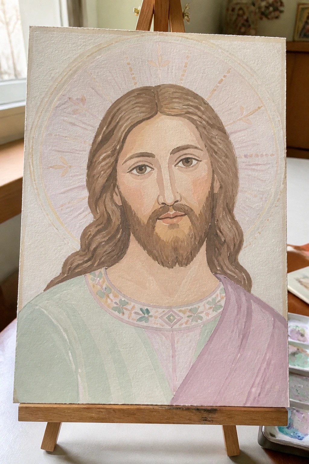 Watercolor Jesus portrait on easel with long hair, beard, halo, green-purple robes