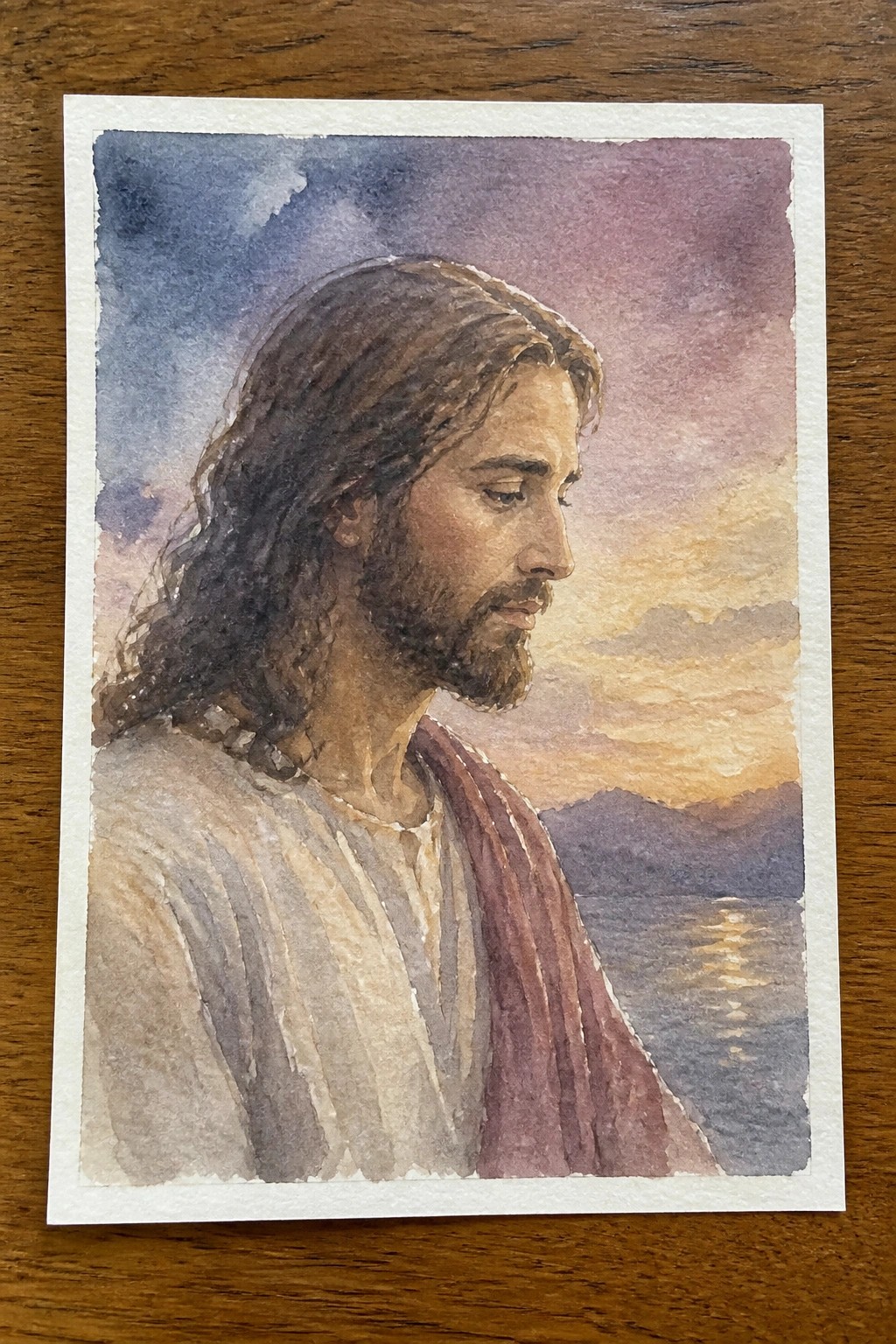 Watercolor portrait of Jesus with long hair, beard, white robe and red sash at sunset.