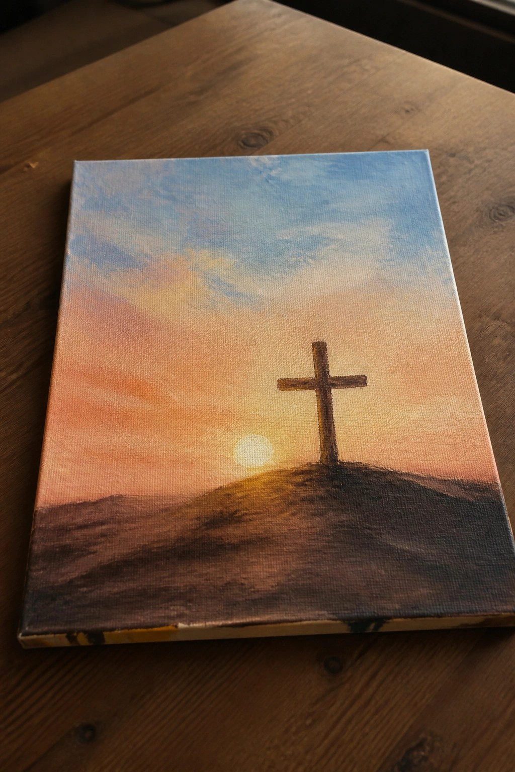 Canvas painting of a cross on a hill under a vibrant sunset sky.