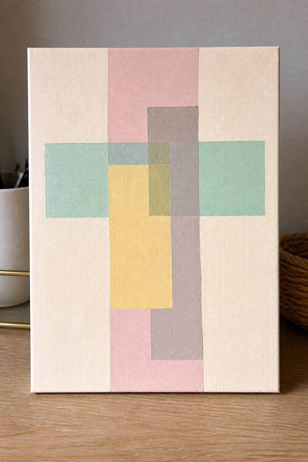A canvas with a cross formed by overlapping pastel rectangles in green, yellow, pink, and gray on a beige background.