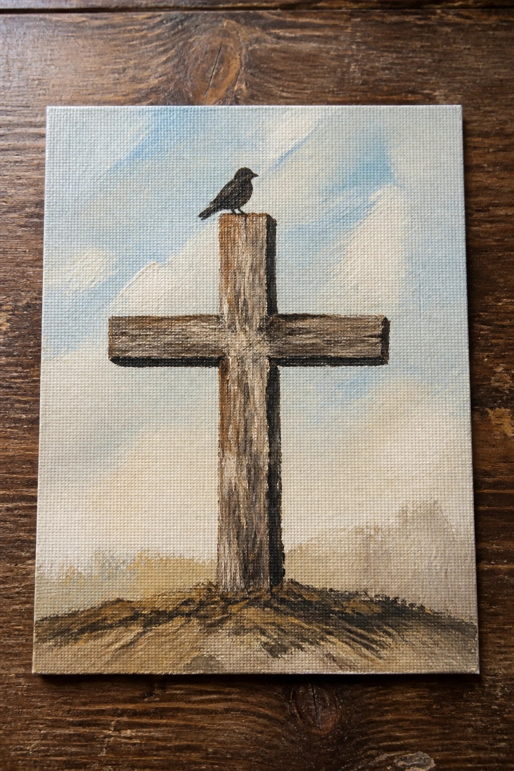 Weathered wooden cross with black bird perched atop under cloudy blue sky painting