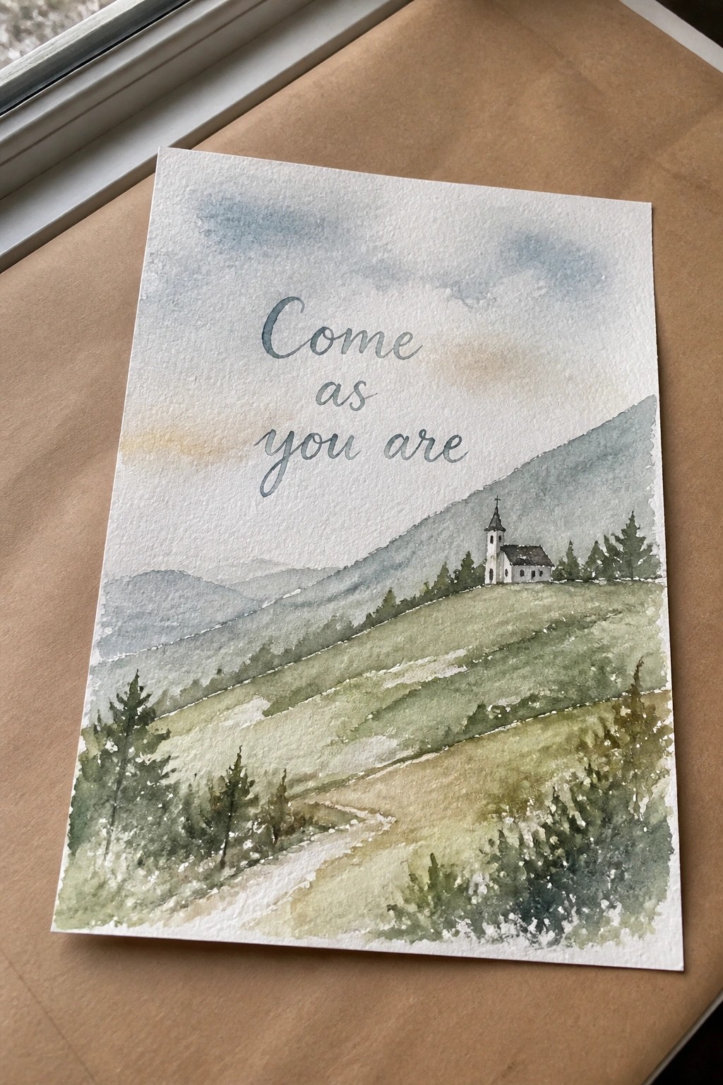 Watercolor landscape of church on green hillside with mountains and 