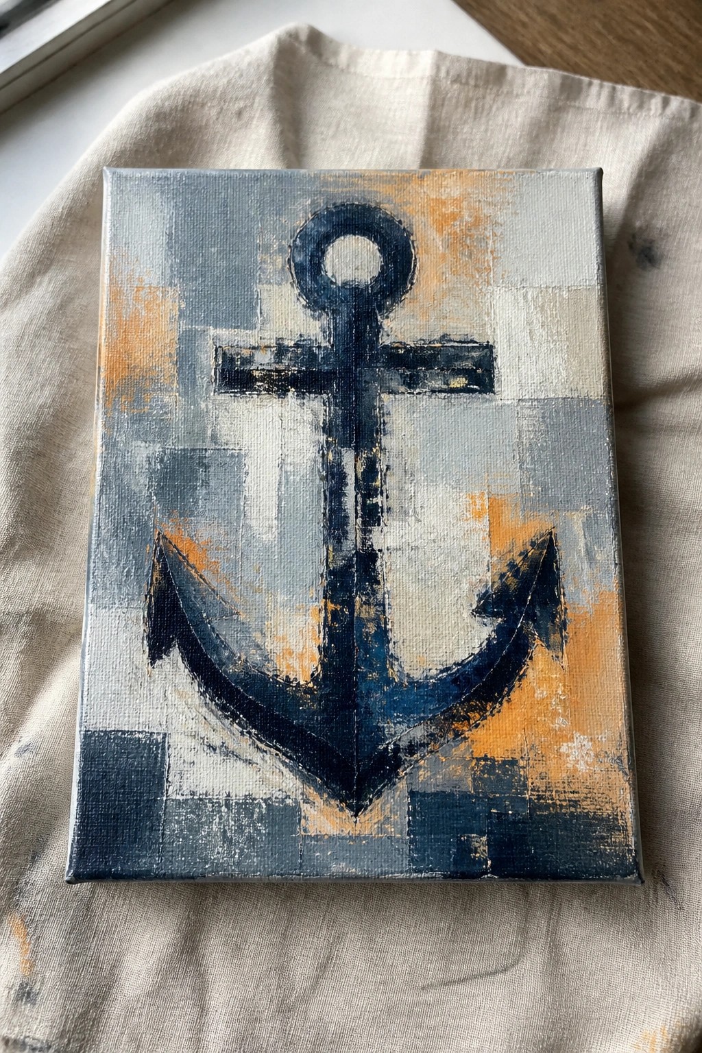 Abstract blue anchor painting on canvas atop stained beige fabric