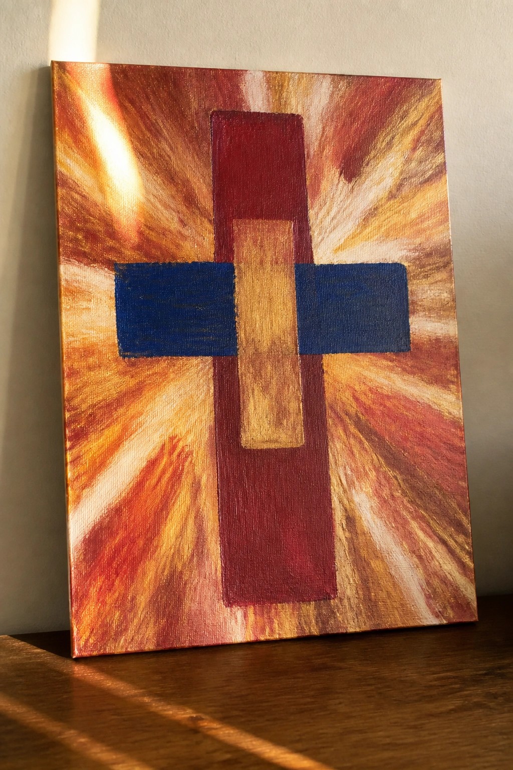 Abstract painting of red-blue-gold cross on fiery radiating orange-red canvas.