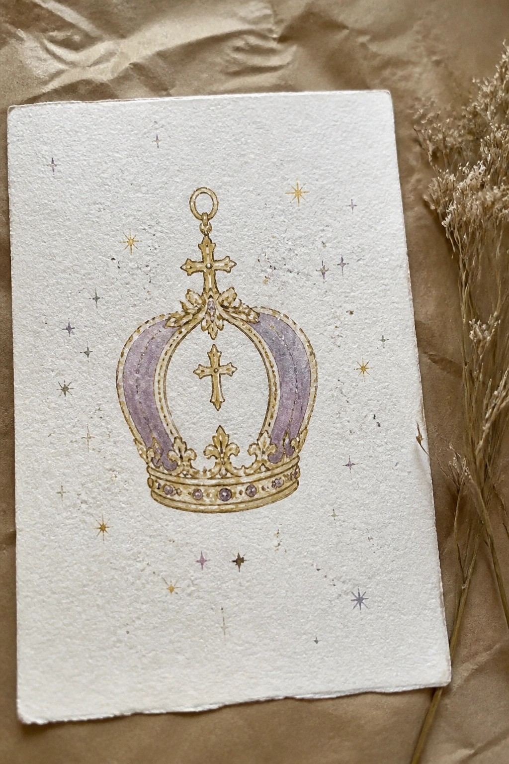 Watercolor painting of ornate purple and gold crown with crosses and stars on paper