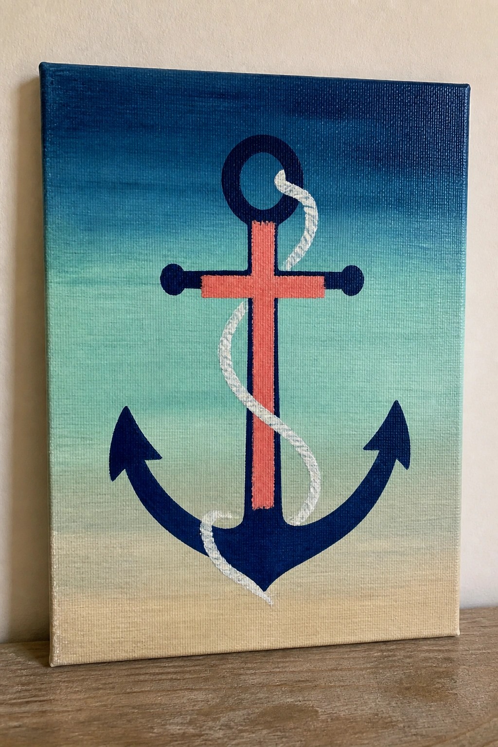 Navy blue anchor with coral crossbar and white rope on ocean-gradient canvas.
