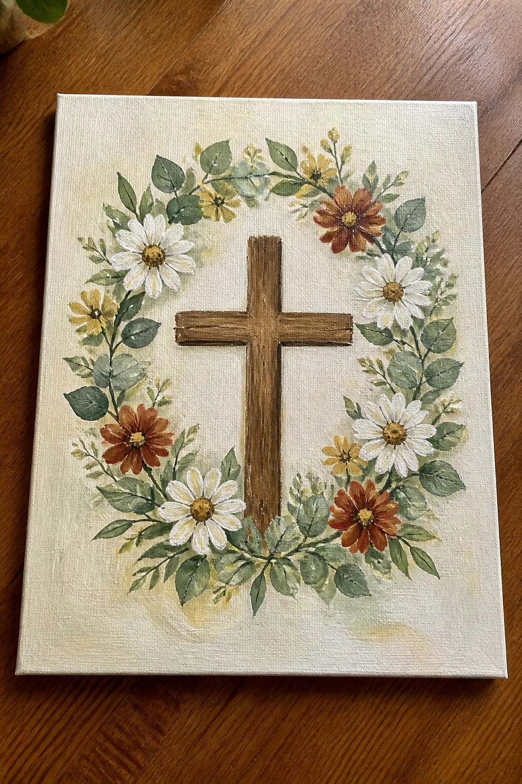 Wooden cross centered in a floral wreath of white daisies and colorful blooms on canvas