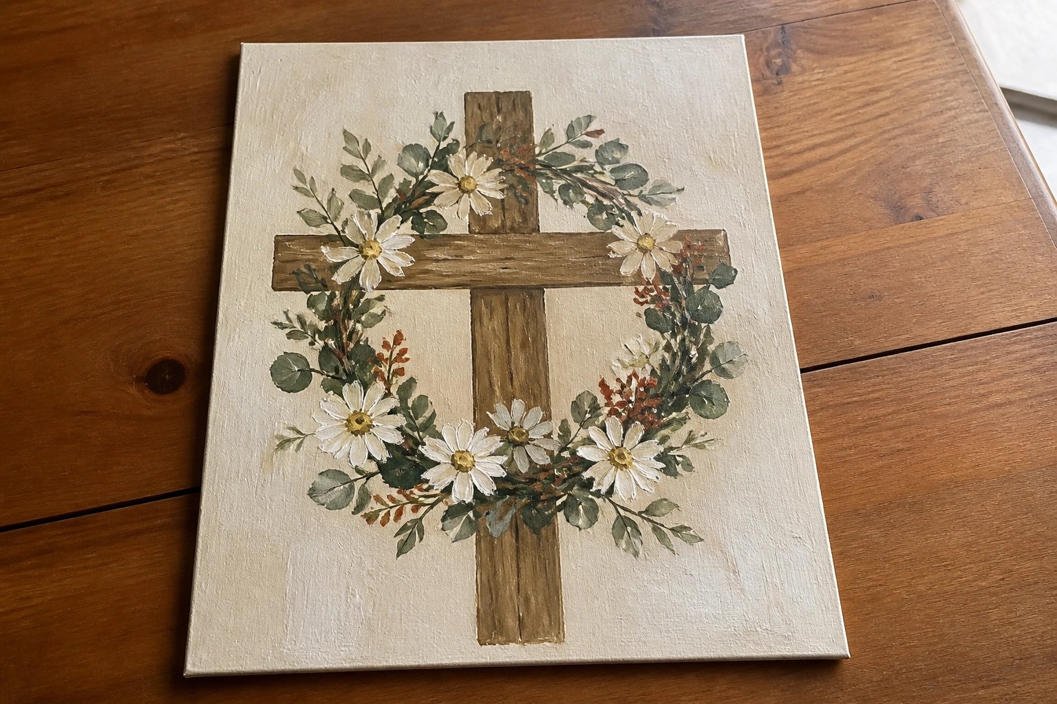 Wooden cross centered in a floral wreath of white daisies and colorful blooms on canvas