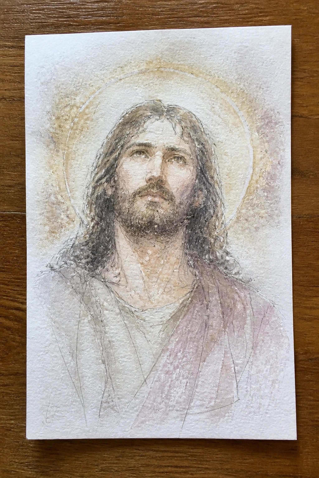 Watercolor of Jesus with long hair, beard, and halo in white and pink robes