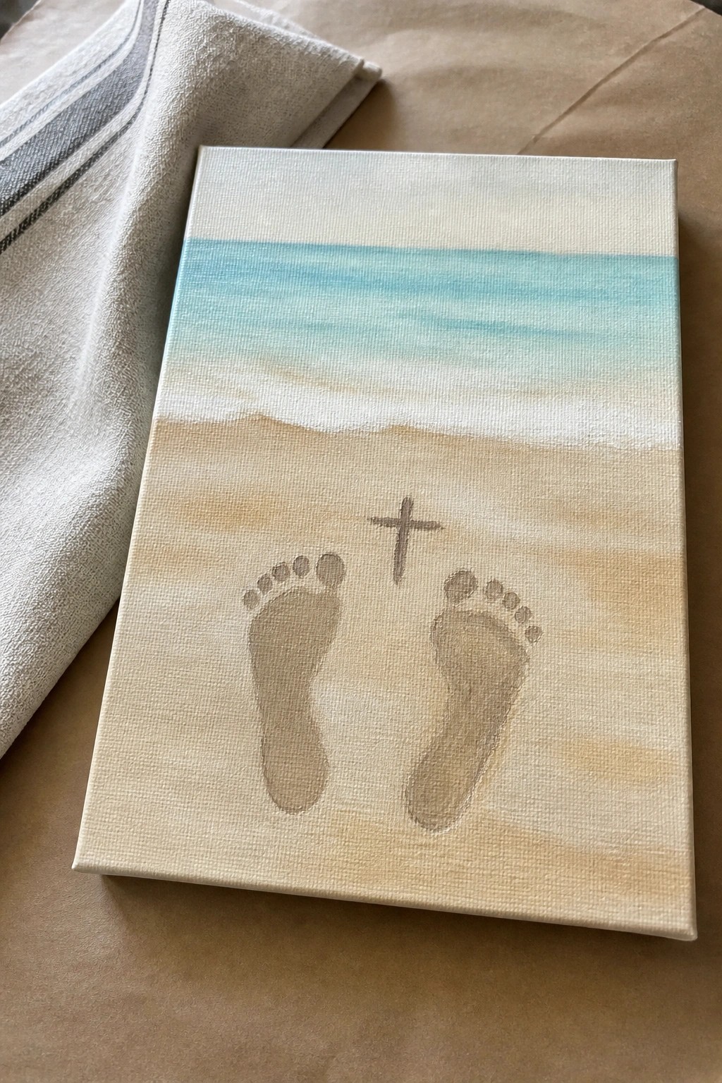 Canvas painting of beach with turquoise ocean, footprints in sand, and cross.
