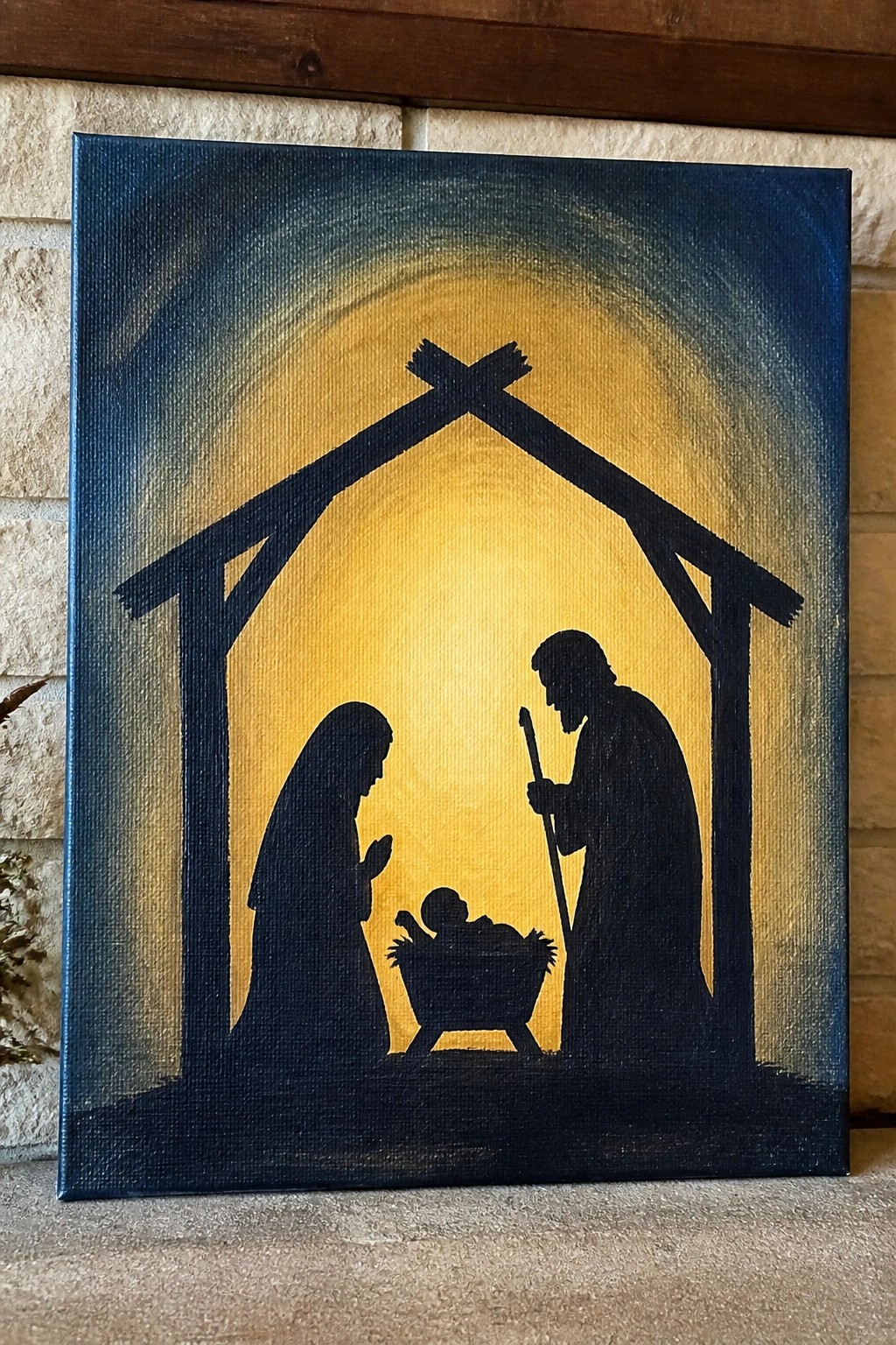 Silhouette nativity scene with Mary, Joseph, and infant in manger under stable.