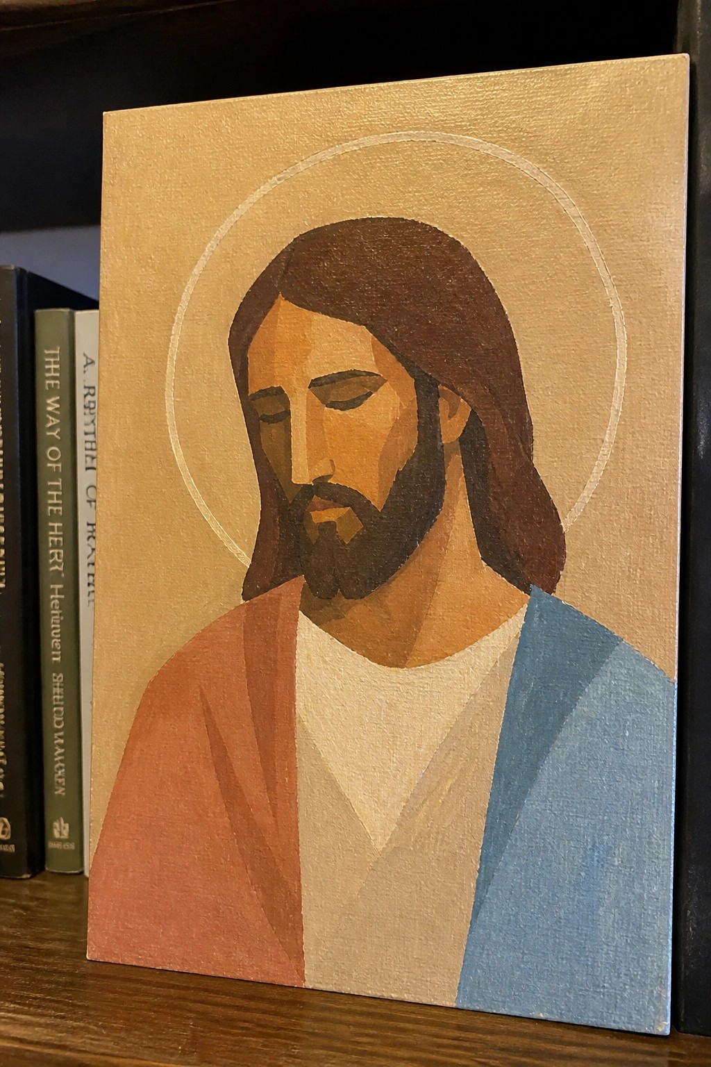 Stylized geometric painting of Jesus with halo, brown hair, beard, red and blue robes