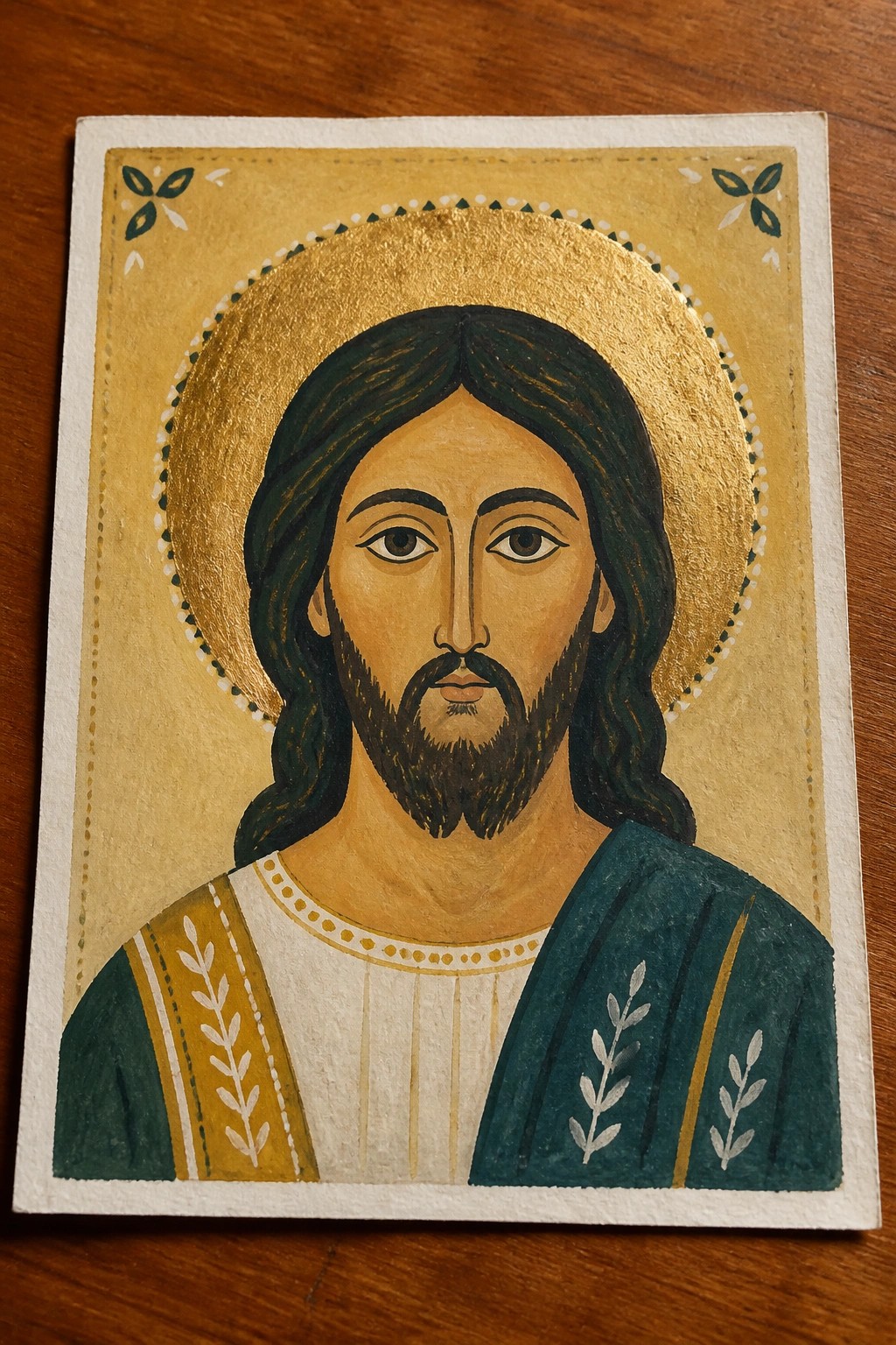 Byzantine-style icon of Jesus with golden halo, long hair, and teal-gold robes.