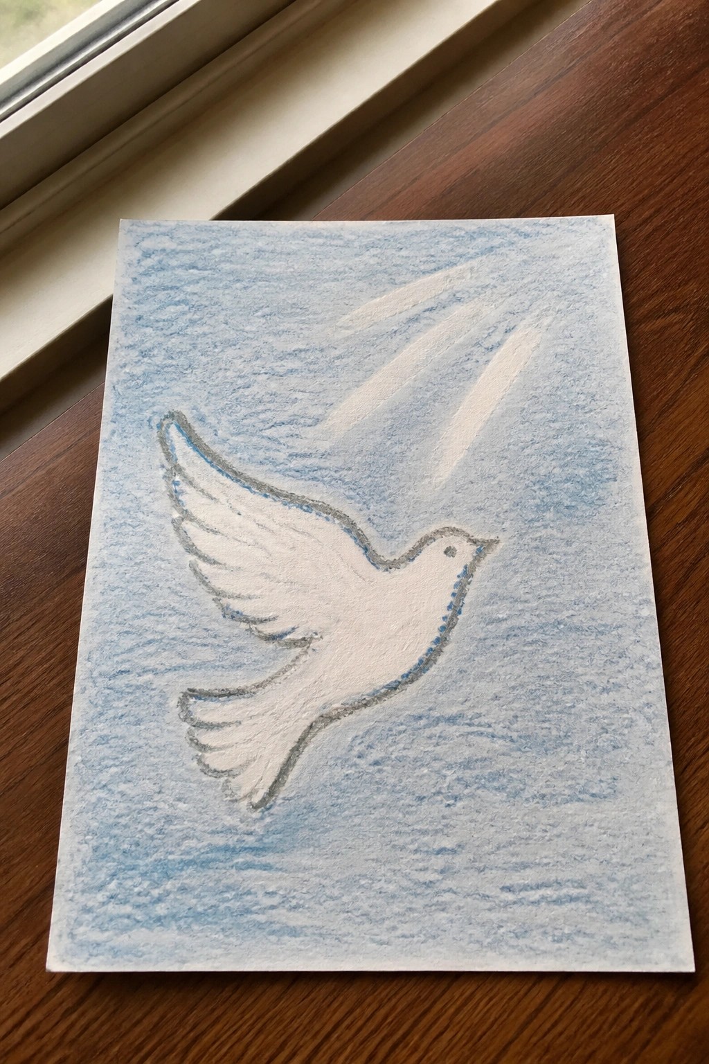 Hand-drawn white dove with blue outline flying on textured light blue paper over wood