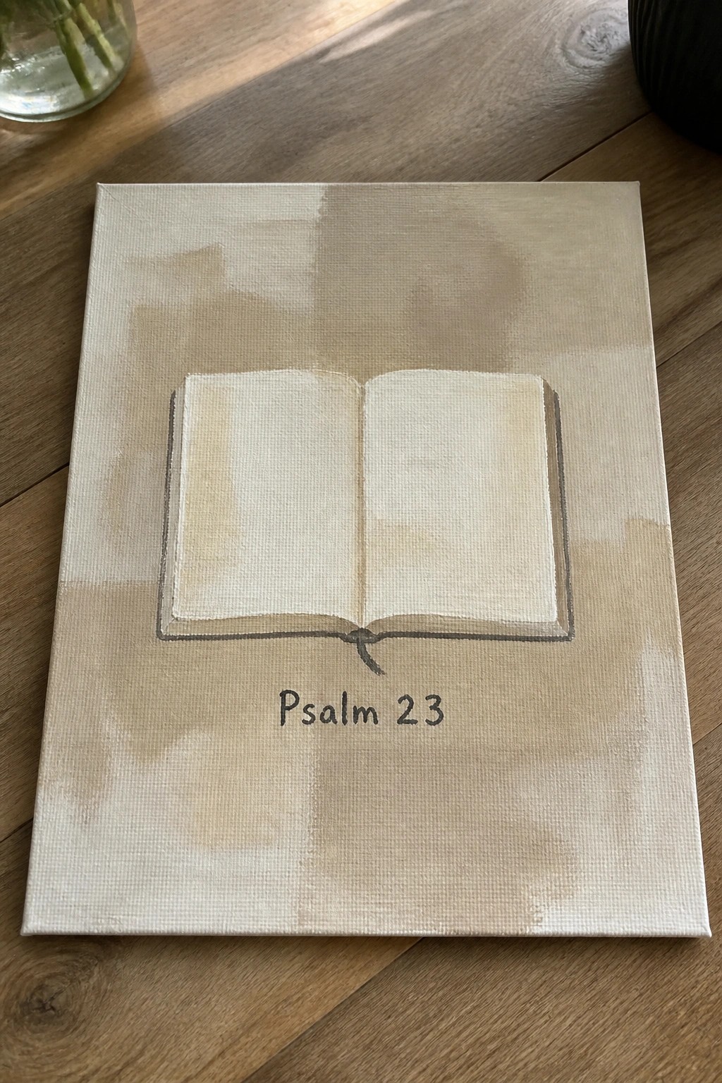 Beige canvas painting of open book with Psalm 23 text below on wood table