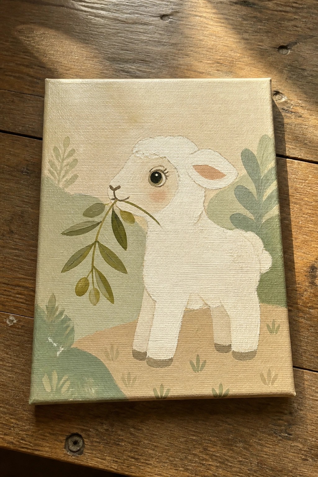 A canvas painting of a white lamb holding a leafy olive branch against a soft green and beige background.