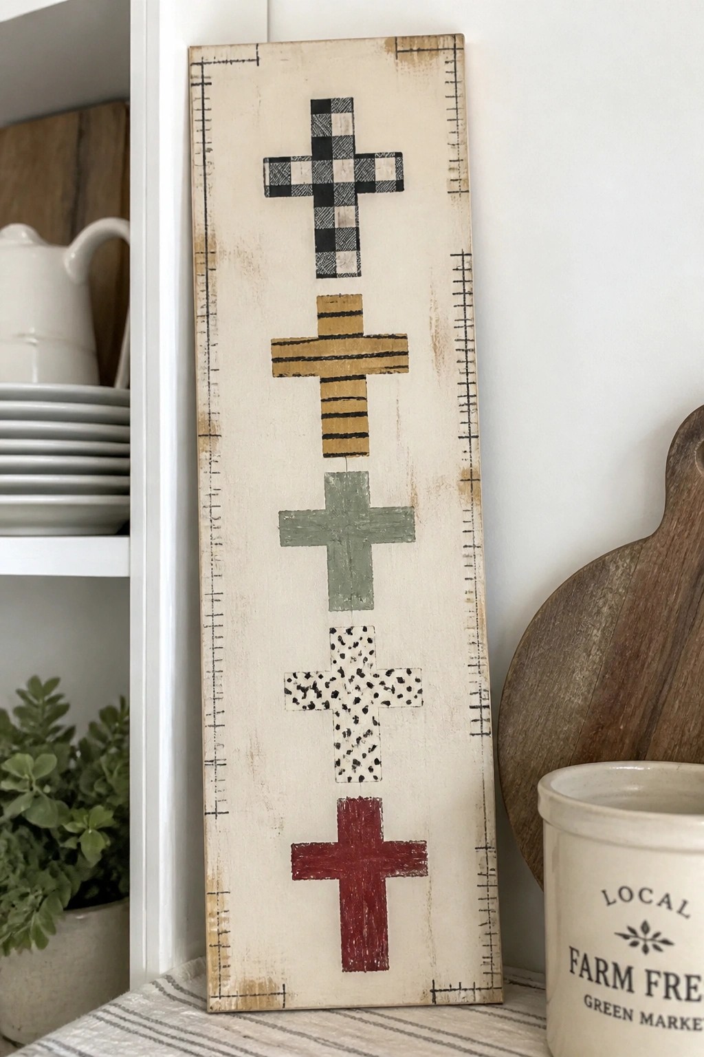 Rustic wooden sign with five patterned crosses in checkered, striped, green, dotted, and red designs.