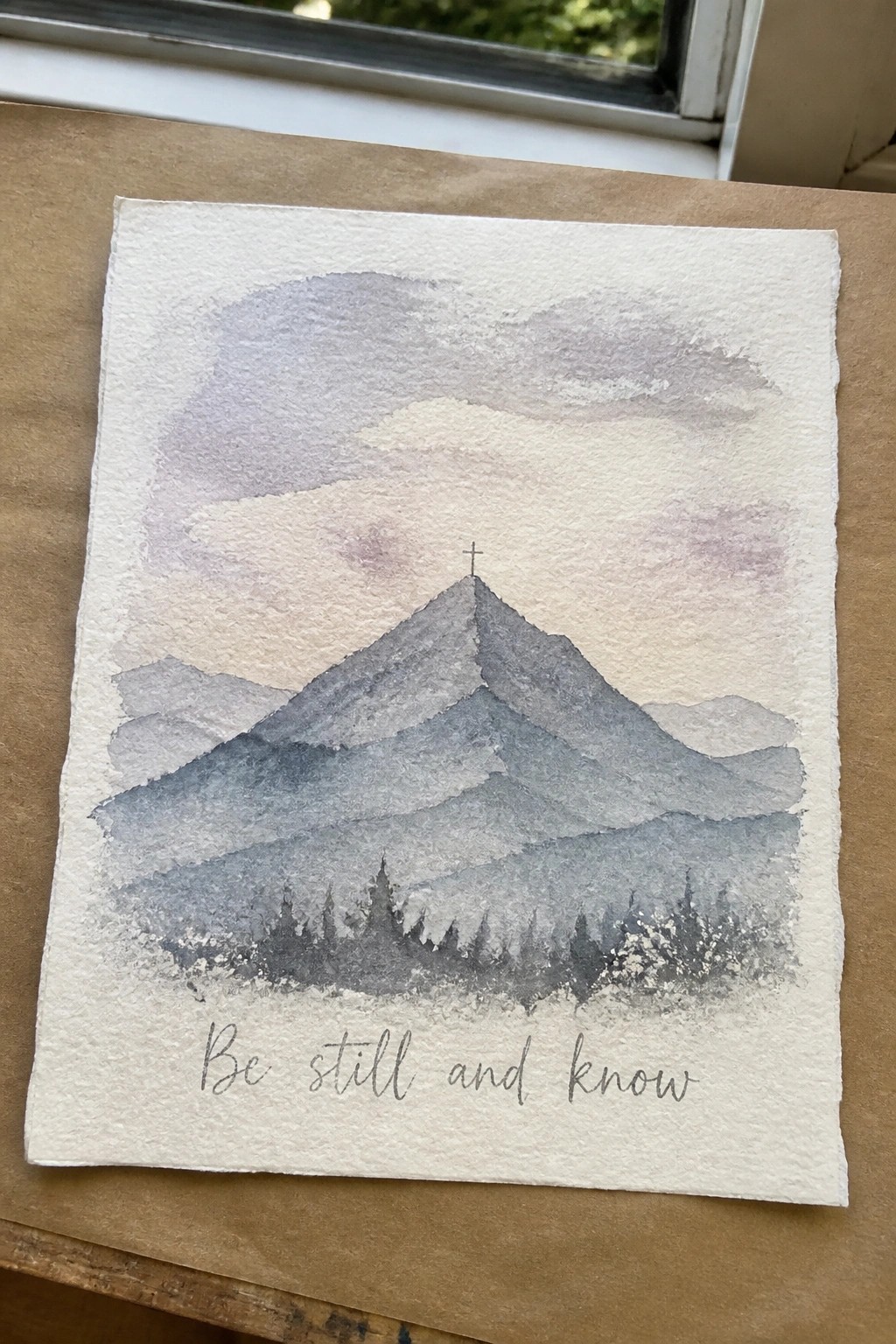 Gray watercolor mountains with summit cross, pine trees, and 